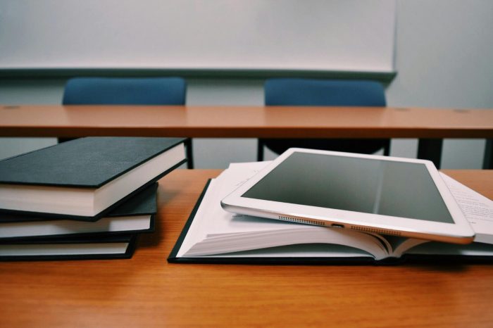 An iPad and stack of books on an empty desk