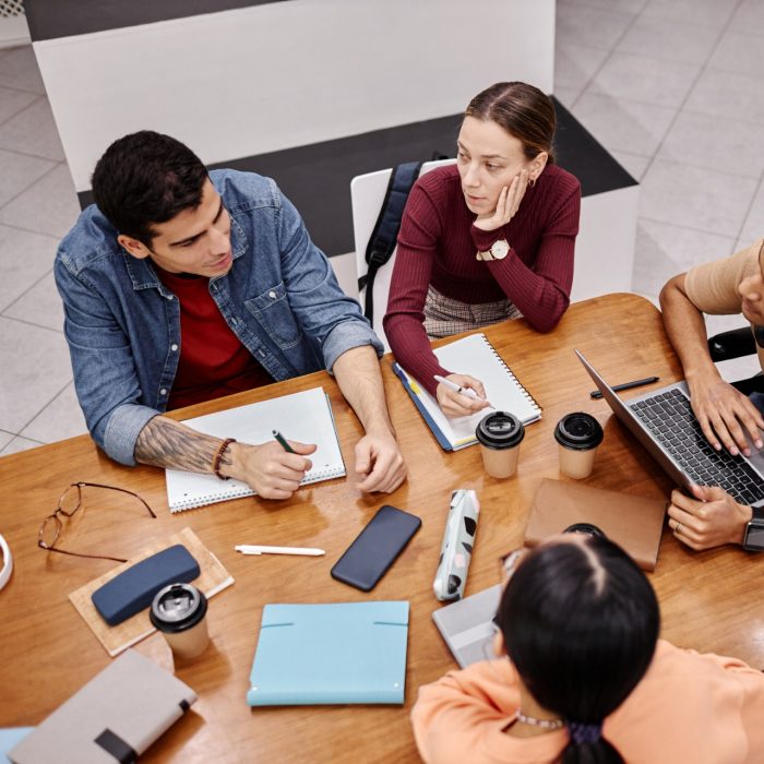 Top view at diverse group of young people studying together at table in college library, inclusivity concept