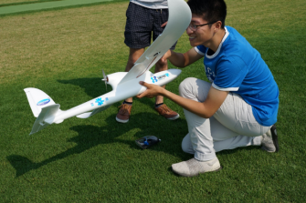 Student on grass with model plane