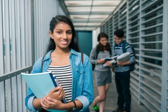 Portrait of a student on her way to class holding books 