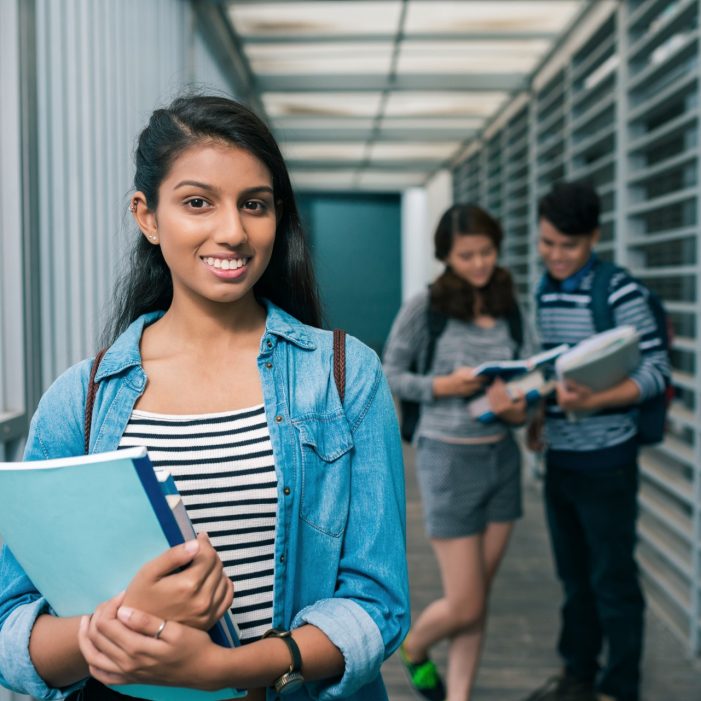 Portrait of a student on her way to class holding books 