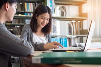 Couple of students studying together at library.