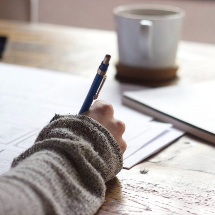 Picture of person signing documents with coffee cup in the background