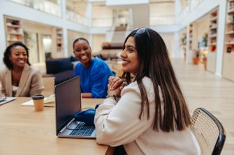 A group of businesswomen are engaged in a marketing meeting within a contemporary office space. They are collaborating effectively, expressing teamwork and female leadership.