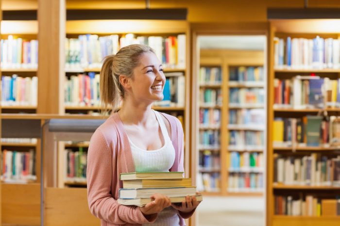 Couple smiling at each other at the library while holding books