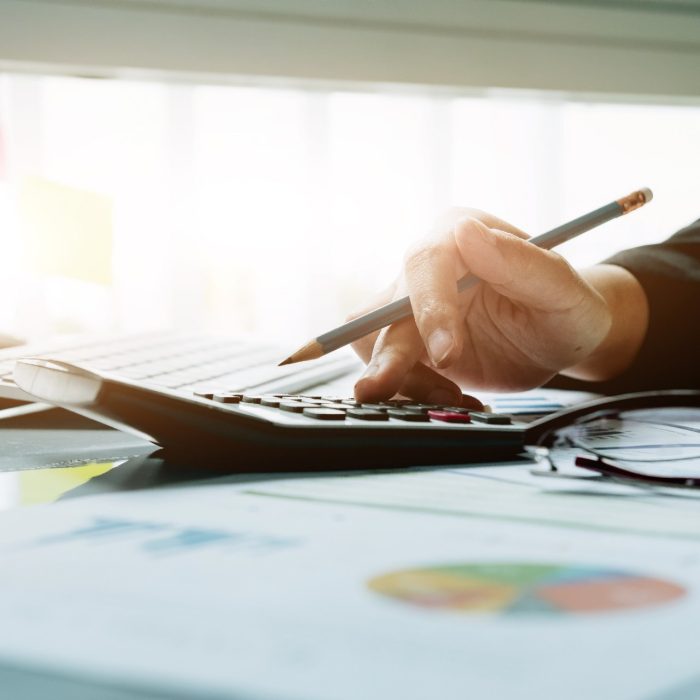 Close up Business woman using calculator and laptop for do math finance on wooden desk in office and business working background, tax, accounting, statistics and analytic research concept
