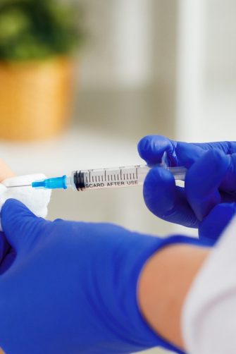 Doctor hands making a vaccination in the shoulder of patient close up