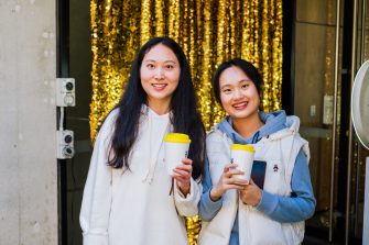 Two happy students with white clothes and white coffee cups