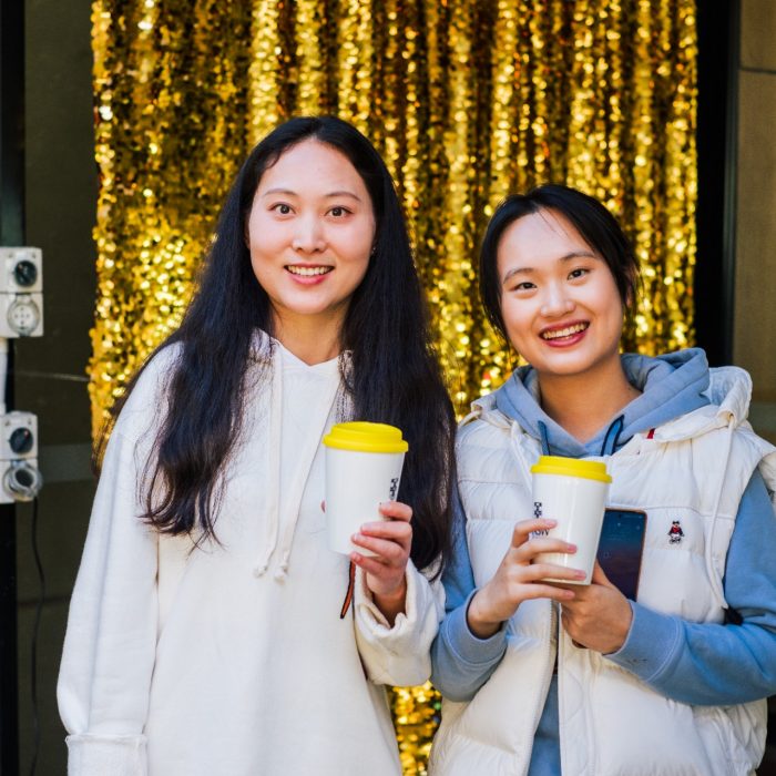 Two happy students with white clothes and white coffee cups