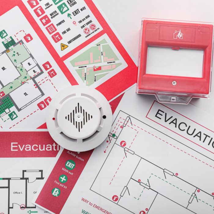 Evacuation plans, smoke detector and manual call point on white background