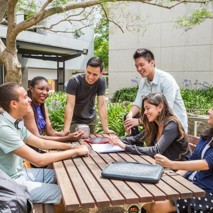 Students together outside at table