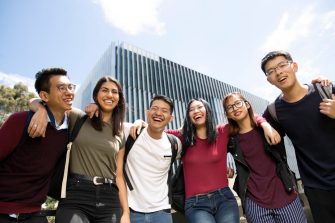 Smiling students standing in front of building