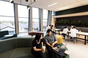 Students talking and studying in common room with bubble tea and laptops