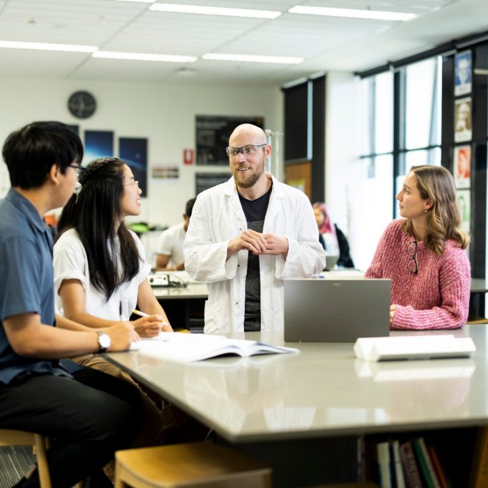 Science Teacher in class discussing with three students