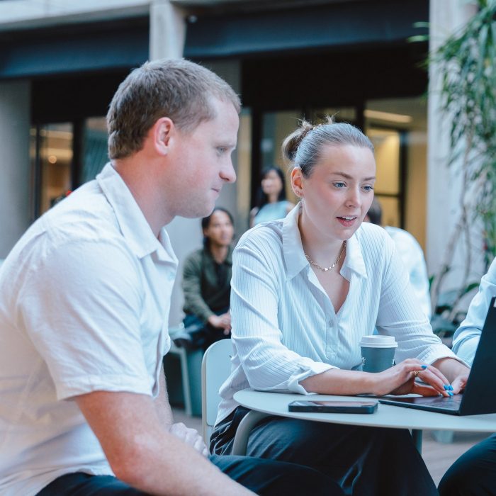 Young lady and man working on laptop in courtyard