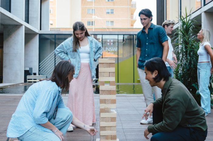 Group of students in courtyard playing a block stacking game