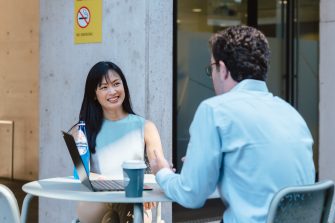 A man and woman sitting at a table with coffee and. a laptop