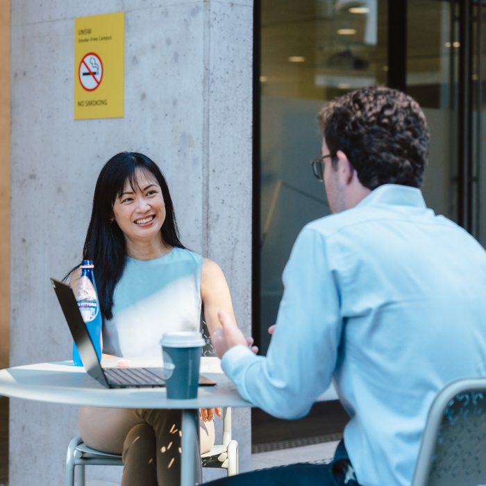 A man and woman sitting at a table with coffee and. a laptop