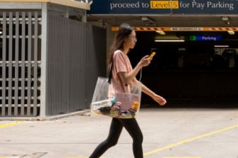 student walking on pedestrian crossing past carpark