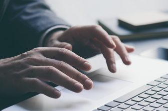 Businessman working on laptop and analysing the financial information at his office. Close up of male hands typing on computer keyboard