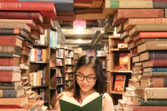 Person reading a book surrounded by other books